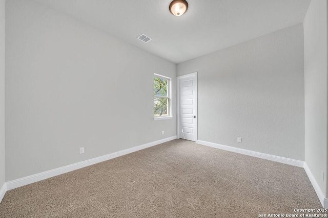 carpeted spare room with visible vents and baseboards