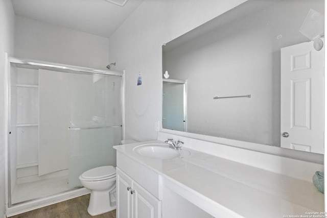 bathroom with hardwood / wood-style floors, vanity, toilet, and walk in shower