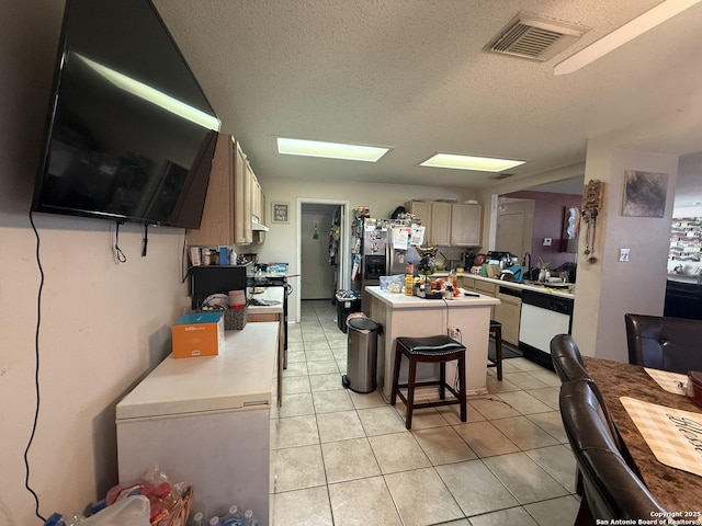 kitchen featuring a breakfast bar, a center island, white dishwasher, stainless steel fridge, and a textured ceiling