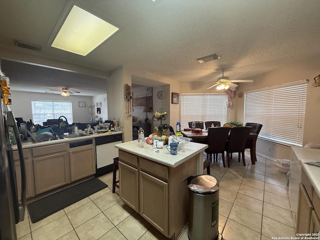 kitchen featuring a textured ceiling, a center island, light tile patterned floors, and white dishwasher