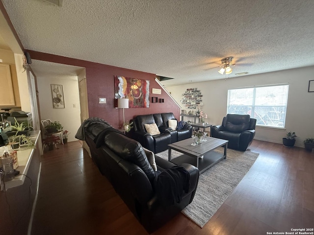 living room featuring ceiling fan, dark wood-type flooring, and a textured ceiling