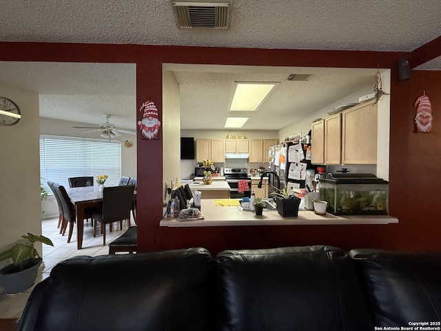 kitchen featuring light tile patterned flooring, appliances with stainless steel finishes, a textured ceiling, and light brown cabinets