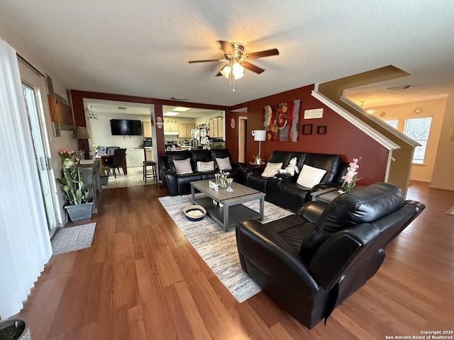 living room with ceiling fan, a healthy amount of sunlight, wood-type flooring, and a textured ceiling