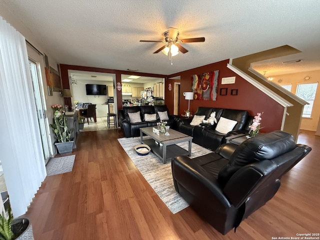 living room with ceiling fan, hardwood / wood-style floors, and a textured ceiling