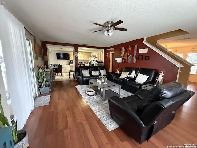 living room with hardwood / wood-style flooring, ceiling fan, and a textured ceiling