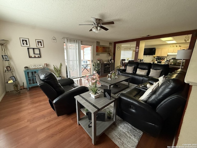 living room featuring wood-type flooring, a textured ceiling, and ceiling fan