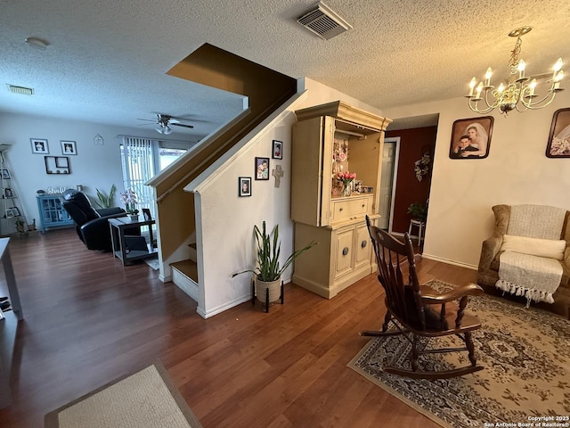 sitting room with dark hardwood / wood-style flooring, ceiling fan with notable chandelier, and a textured ceiling