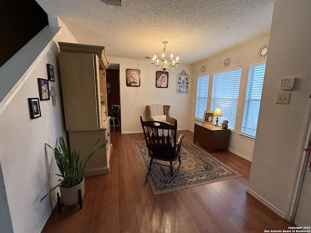 dining area with a notable chandelier, a textured ceiling, and dark hardwood / wood-style flooring