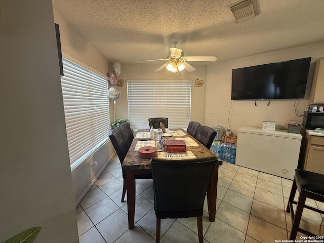 dining space with light tile patterned flooring, ceiling fan, and a textured ceiling