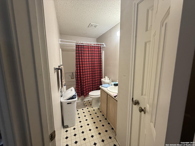 bathroom with vanity, curtained shower, toilet, and a textured ceiling