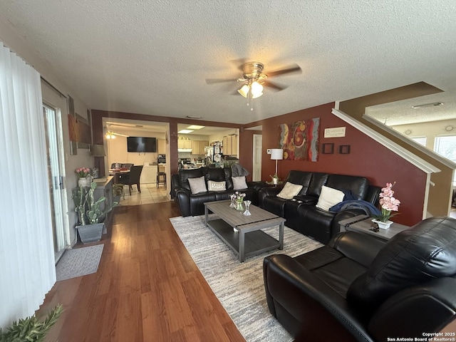 living room with ceiling fan, wood-type flooring, and a textured ceiling