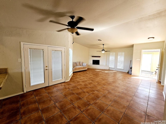 unfurnished living room featuring french doors, tile patterned floors, ceiling fan, a fireplace, and a textured ceiling