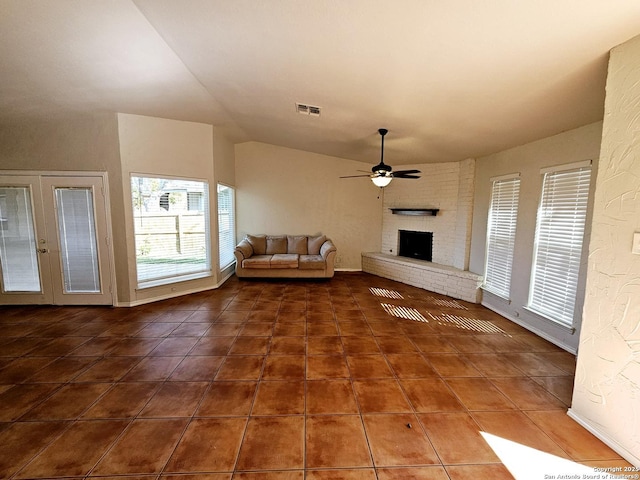 unfurnished living room featuring ceiling fan, dark tile patterned floors, a fireplace, and lofted ceiling