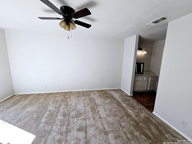 unfurnished living room featuring dark carpet and ceiling fan