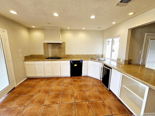 kitchen with kitchen peninsula, custom exhaust hood, dishwashing machine, light tile patterned floors, and white cabinets