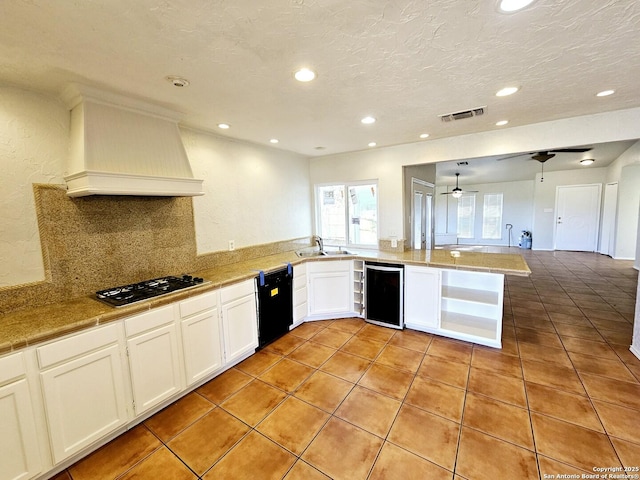 kitchen with ceiling fan, dishwasher, premium range hood, kitchen peninsula, and stainless steel gas stovetop