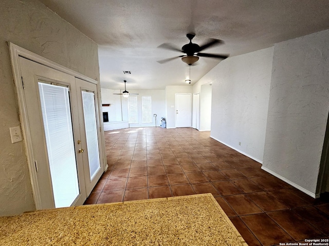 interior space featuring a textured ceiling, french doors, dark tile patterned flooring, and vaulted ceiling