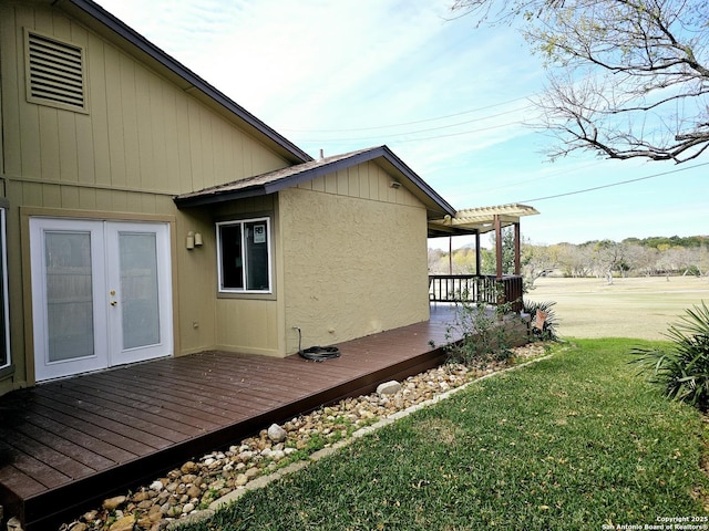 view of property exterior featuring a yard, french doors, and a deck