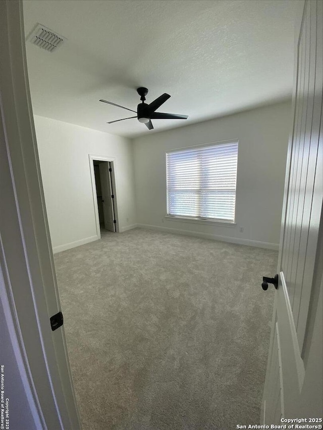 carpeted spare room featuring ceiling fan and a textured ceiling