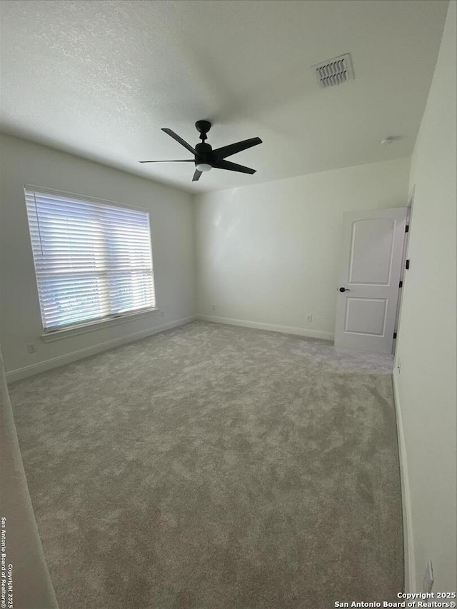 spare room with carpet, a textured ceiling, and ceiling fan