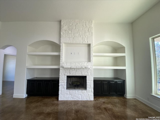 unfurnished living room with built in shelves, a fireplace, and a wealth of natural light