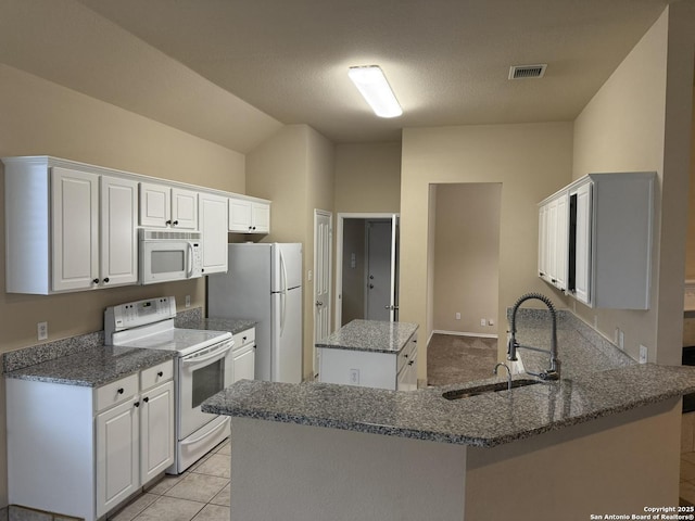 kitchen with kitchen peninsula, white appliances, sink, light tile patterned floors, and white cabinets