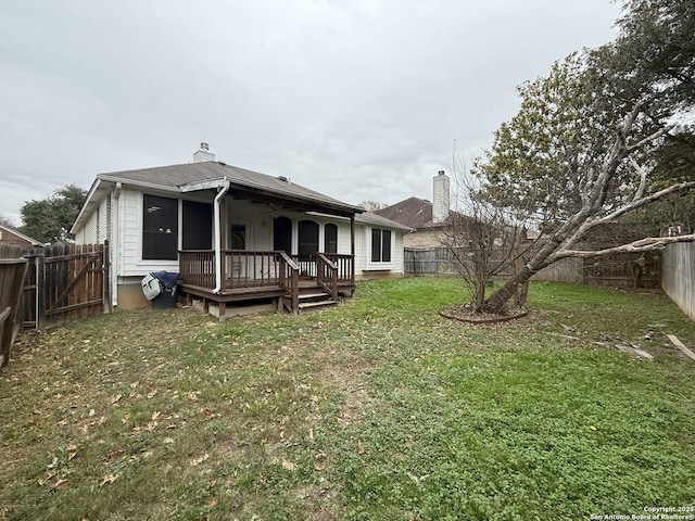 rear view of house featuring a lawn and a wooden deck