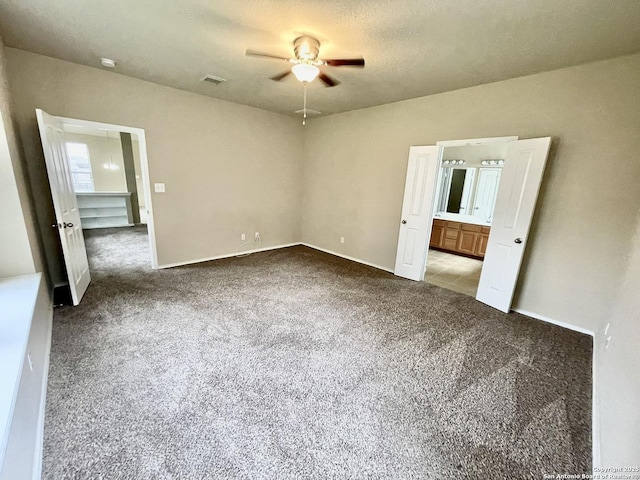 unfurnished bedroom with ceiling fan, light colored carpet, a textured ceiling, and ensuite bath