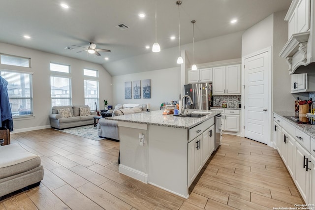 kitchen featuring white cabinets, an island with sink, appliances with stainless steel finishes, and tasteful backsplash