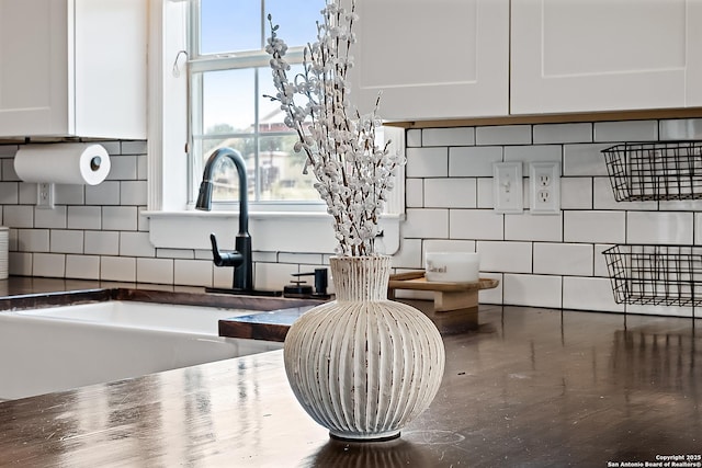 details featuring decorative backsplash, white cabinetry, and sink