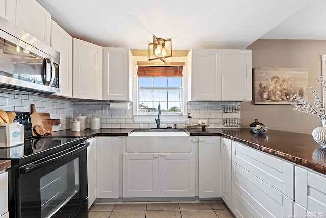 kitchen with backsplash, sink, black electric range, white cabinetry, and light tile patterned flooring