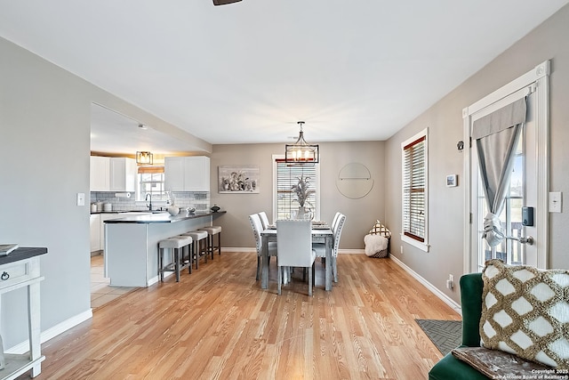 dining room featuring a notable chandelier, sink, and light hardwood / wood-style flooring