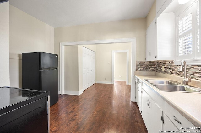 kitchen with white cabinetry, sink, black refrigerator, and dark wood-type flooring