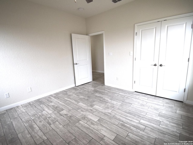 unfurnished bedroom with ceiling fan, light wood-type flooring, and a closet