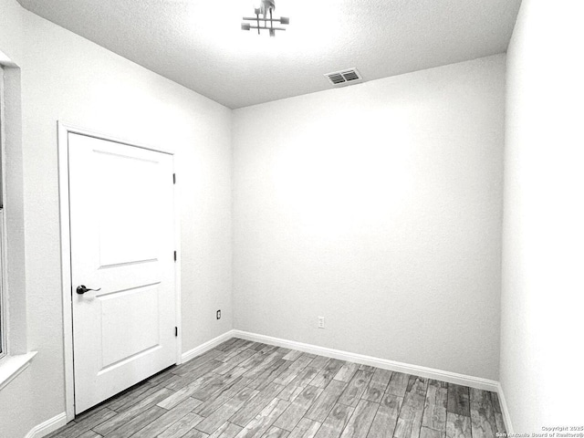 unfurnished room featuring a textured ceiling and light hardwood / wood-style floors