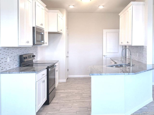 kitchen featuring white cabinets, dark stone countertops, kitchen peninsula, and stainless steel appliances