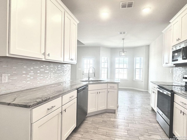 kitchen with kitchen peninsula, stainless steel appliances, sink, pendant lighting, and white cabinets