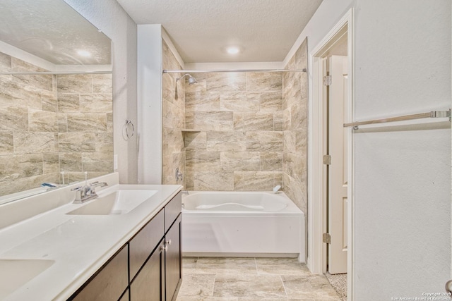 bathroom with tiled shower / bath combo, a textured ceiling, and vanity