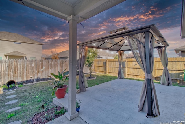 patio terrace at dusk featuring a gazebo and a lawn