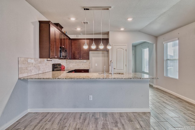 kitchen featuring light stone countertops, pendant lighting, lofted ceiling, and black appliances