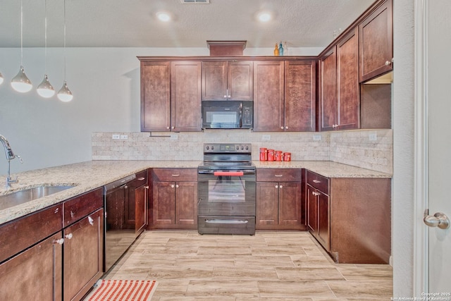 kitchen featuring black appliances, pendant lighting, light stone counters, and sink