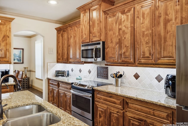 kitchen featuring sink, crown molding, tasteful backsplash, light stone counters, and stainless steel appliances