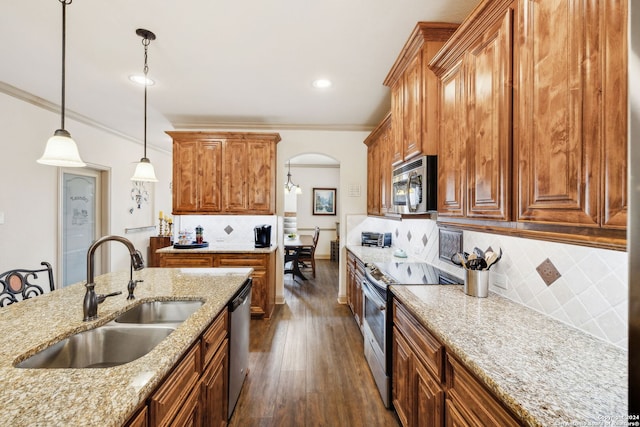 kitchen featuring sink, tasteful backsplash, light stone counters, pendant lighting, and appliances with stainless steel finishes