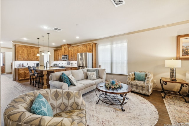 living room featuring dark hardwood / wood-style floors, crown molding, and sink