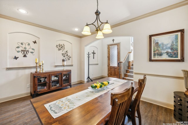 dining area with a chandelier, ornamental molding, and dark wood-type flooring