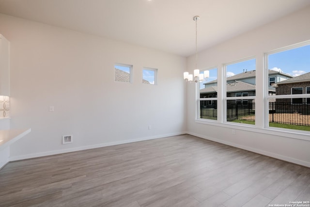 unfurnished dining area with light hardwood / wood-style floors and an inviting chandelier