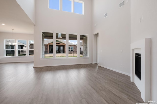 unfurnished living room with a chandelier, a towering ceiling, and dark hardwood / wood-style floors