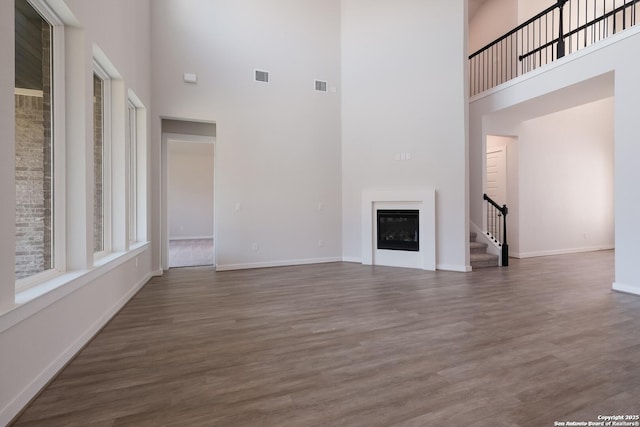 unfurnished living room featuring a towering ceiling and dark wood-type flooring