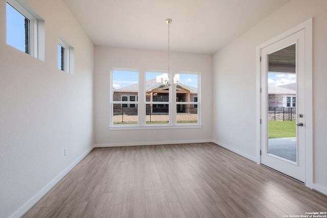 unfurnished dining area with light wood-type flooring and a chandelier