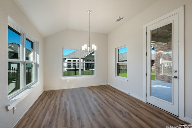 unfurnished dining area with a notable chandelier, wood-type flooring, and lofted ceiling